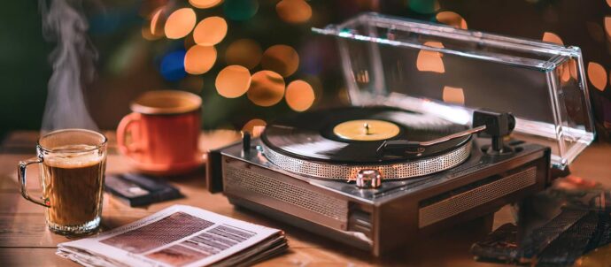 Tekoälyllä luotu valokuva, jossa levysoitin, höyryävä kahvikuppi ja aikakausilehti puisen tason päällä, tausta sumennettu.