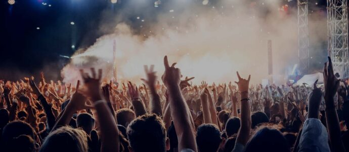 Tekoälyllä luotu kuva ulkoilmakonsertista yleisön keskellä, taustalla savussa oleva valaistu lava .